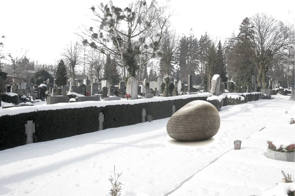 von KGRUPPE Architekten Basel - Verschneiter Friedhof mit vielen Grabsteinen, schneebedecktem Boden und Bäumen im Hintergrund; im Vordergrund ein grosser Stein mit eingraviertem Text.