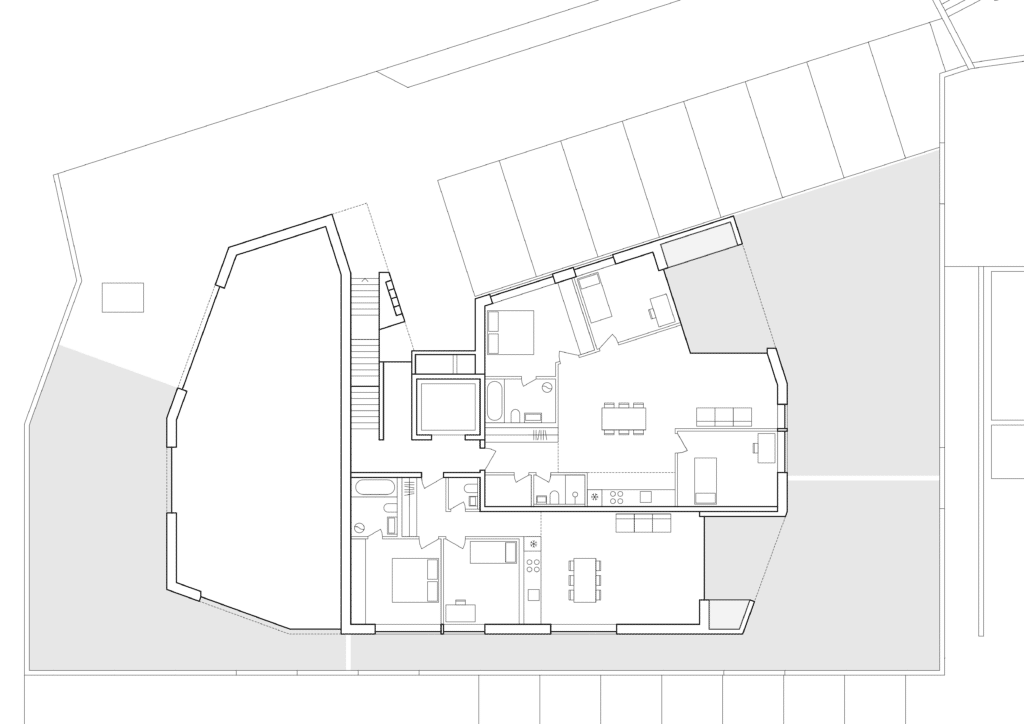 von KGRUPPE Architekten Basel - Grundriss einer Wohnung mit zwei Schlafzimmern, zwei Badezimmern, Küche, Essbereich und Wohnzimmer. Draussen befinden sich Stellplätze für Autos.