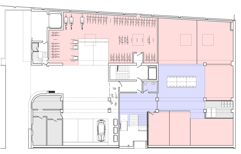 von KGRUPPE Architekten Basel - Grundriss eines Gebäudes mit farblich markierten Bereichen in Rot und Blau. Links oben befinden sich Arbeitsplätze. Rechts daneben ist ein grosser, offener Raum mit Tischen und Stühlen. Unten links eine Garage mit Fahrzeug.